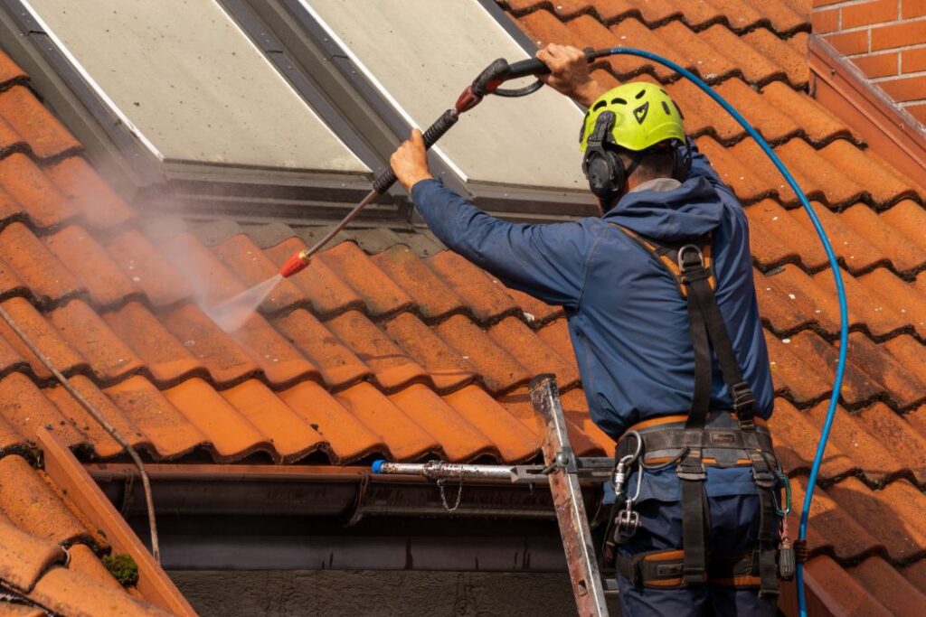 worker washing the roof with pressurized water - Rensfliser - Rensfliser Hvad koster en tagrens?
